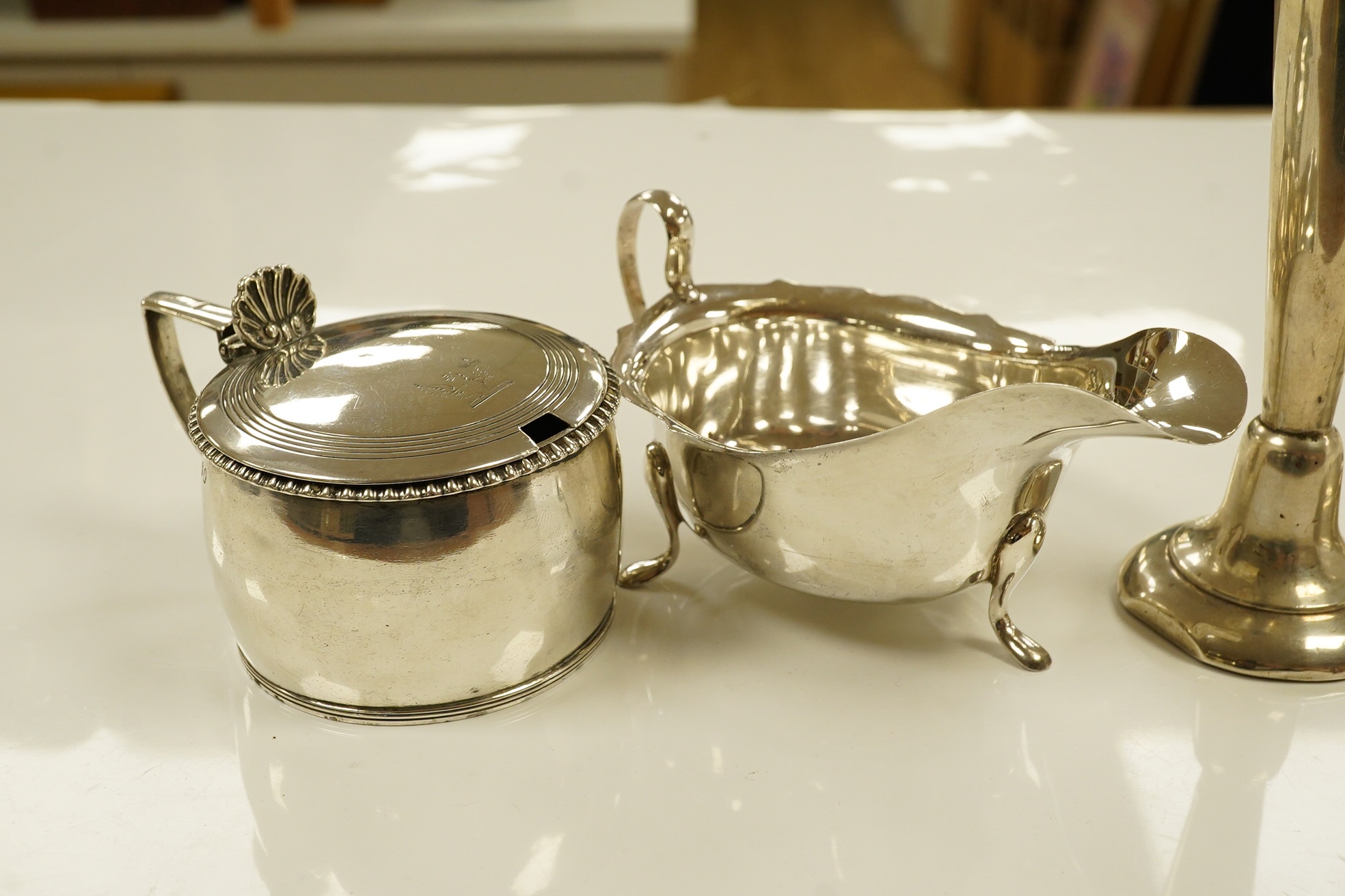 A George VI silver sauceboat, a George III drum mustard, a George V cigarette case and a loaded specimen vase, 10.5 oz of weighable silver. Condition - mustard lacks liner, vase dented, otherwise good